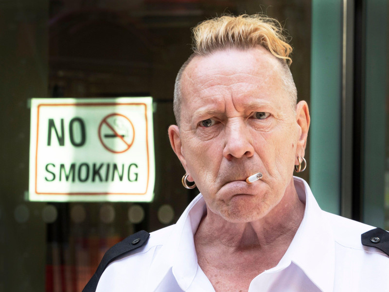 2G8R325 John Joseph Lydon, also known by his stage name Johnny Rotten arrives at court smoking a cigarette as he gives evidence against his band
